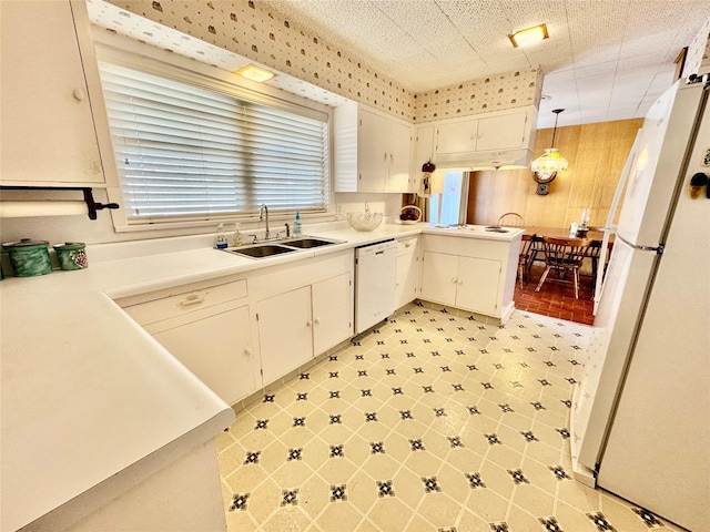 kitchen with white cabinetry, sink, decorative light fixtures, and white appliances