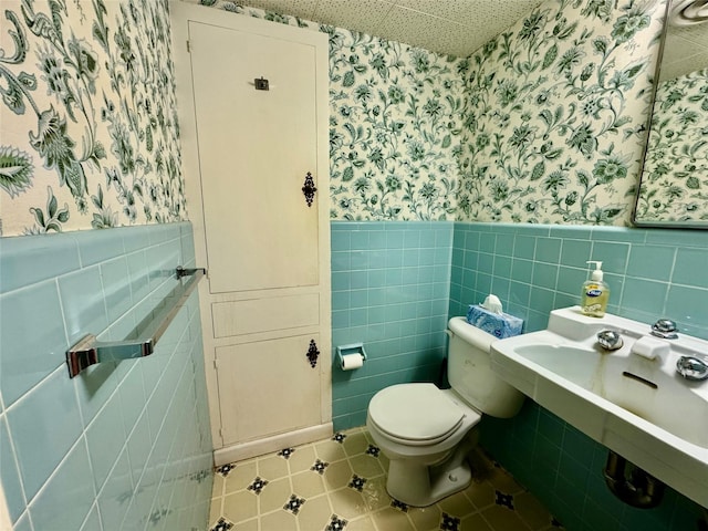 bathroom featuring tile walls, tile patterned floors, and toilet