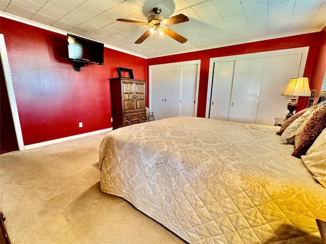 carpeted bedroom with multiple closets, ceiling fan, and ornamental molding