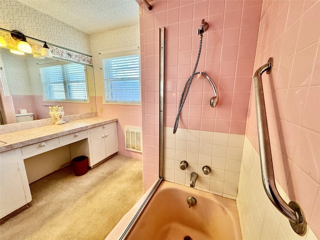 full bathroom with tile walls, tiled shower / bath combo, vanity, a textured ceiling, and toilet