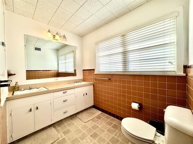 bathroom with vanity, toilet, and tile walls