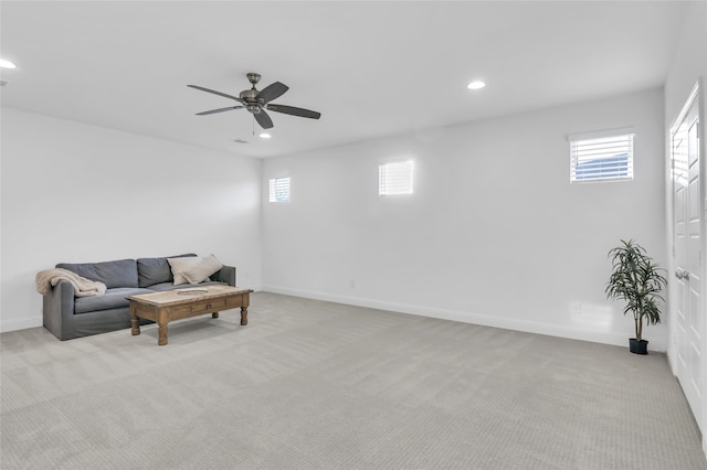 living area featuring ceiling fan, light carpet, and a wealth of natural light