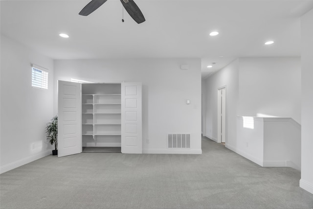 interior space featuring ceiling fan, light colored carpet, and a closet