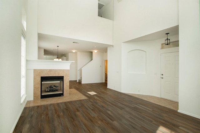 unfurnished living room featuring a high ceiling, a tile fireplace, and dark wood-type flooring