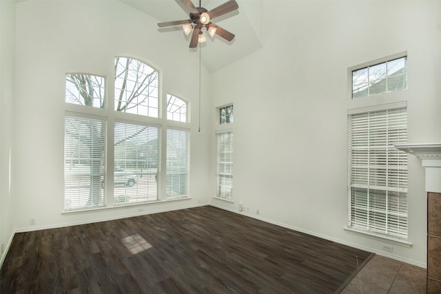 unfurnished living room featuring ceiling fan, a towering ceiling, and dark hardwood / wood-style flooring