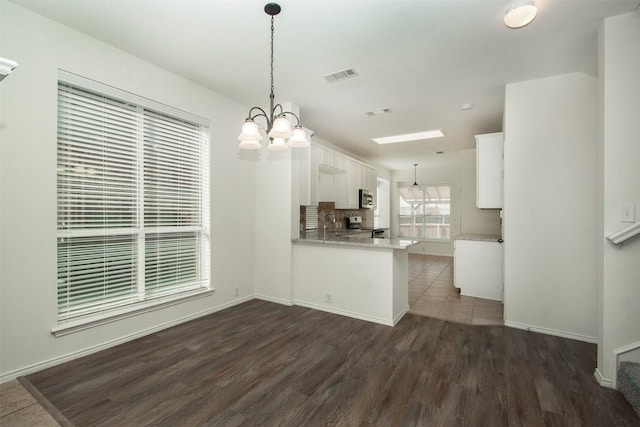 kitchen featuring white cabinetry, appliances with stainless steel finishes, kitchen peninsula, and hanging light fixtures