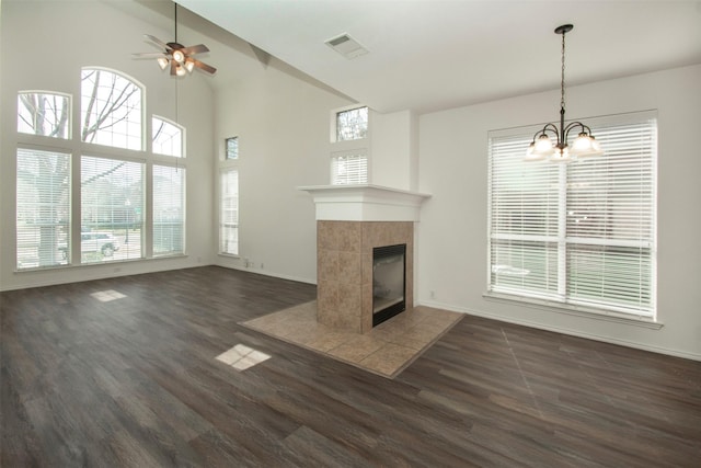 unfurnished living room with high vaulted ceiling, ceiling fan with notable chandelier, a tile fireplace, and dark hardwood / wood-style floors