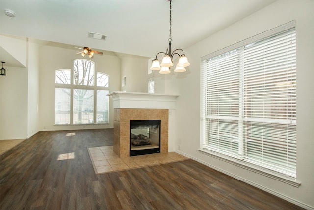 unfurnished living room with a tile fireplace, dark hardwood / wood-style floors, and ceiling fan with notable chandelier