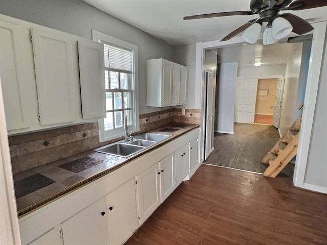 kitchen featuring tasteful backsplash, dark wood-style flooring, white cabinetry, and a sink