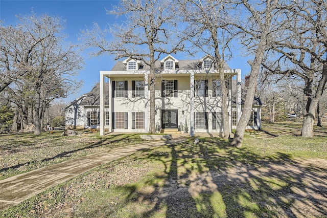 neoclassical home with a front yard, french doors, and a balcony