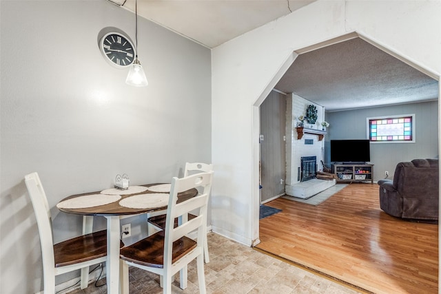 dining room with hardwood / wood-style floors, a textured ceiling, and a fireplace