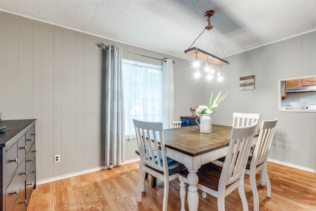 dining room with crown molding, a textured ceiling, and light wood-type flooring