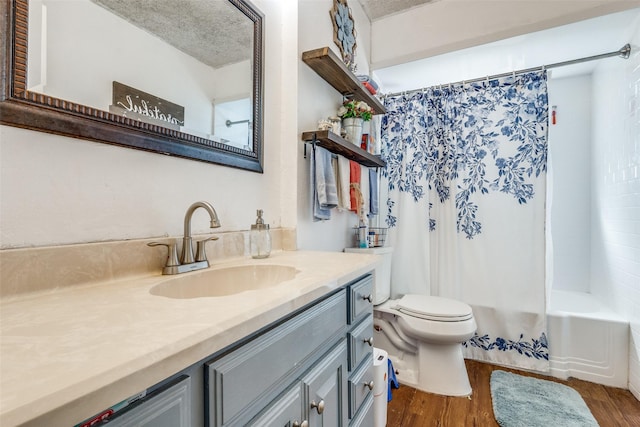 full bathroom with hardwood / wood-style flooring, vanity, shower / tub combo, toilet, and a textured ceiling