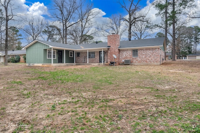 back of property with cooling unit, brick siding, and a chimney