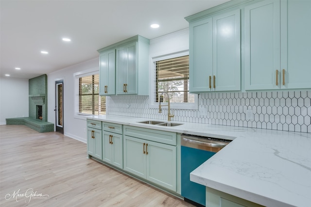 kitchen with a fireplace, decorative backsplash, a sink, light wood-type flooring, and dishwashing machine