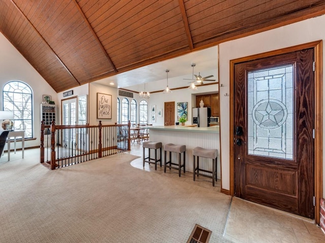 carpeted entrance foyer featuring an inviting chandelier, wooden ceiling, and high vaulted ceiling