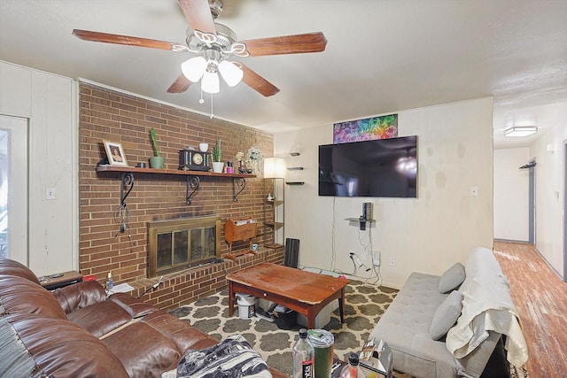 living room featuring hardwood / wood-style flooring, a brick fireplace, and ceiling fan