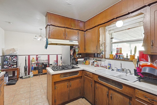 kitchen featuring stainless steel gas stovetop, tasteful backsplash, sink, light tile patterned floors, and kitchen peninsula