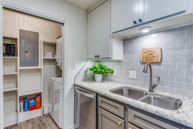 kitchen featuring sink, electric panel, light hardwood / wood-style floors, light stone countertops, and stainless steel dishwasher