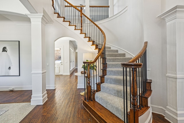 stairway with ornate columns, a high ceiling, and hardwood / wood-style flooring