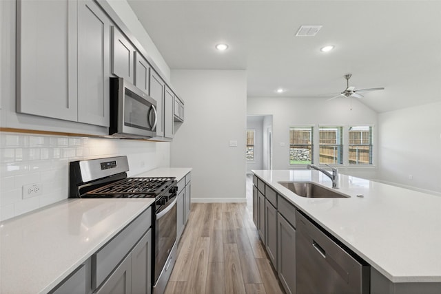 kitchen featuring sink, gray cabinetry, light hardwood / wood-style flooring, appliances with stainless steel finishes, and backsplash