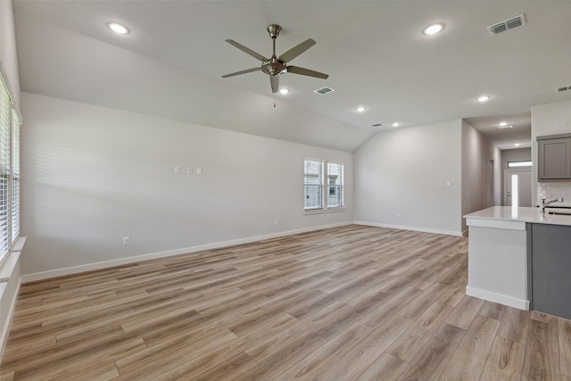 unfurnished living room featuring sink, vaulted ceiling, light hardwood / wood-style floors, and ceiling fan