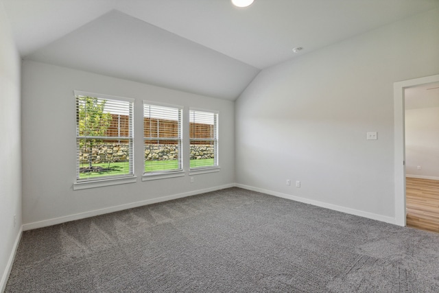 spare room featuring vaulted ceiling and carpet flooring