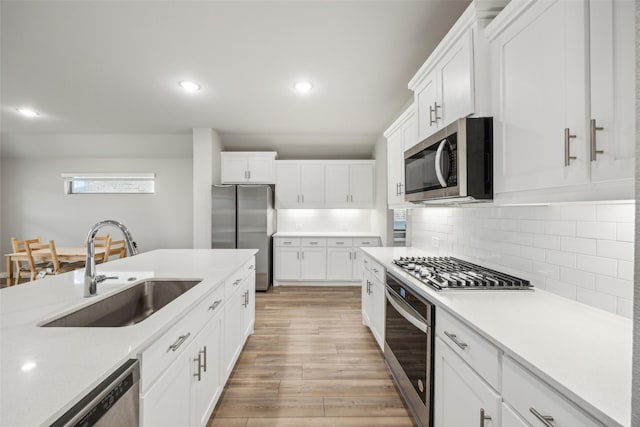 kitchen with white cabinetry, sink, light hardwood / wood-style flooring, and appliances with stainless steel finishes