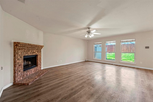 unfurnished living room featuring a textured ceiling, a fireplace, dark hardwood / wood-style floors, and ceiling fan