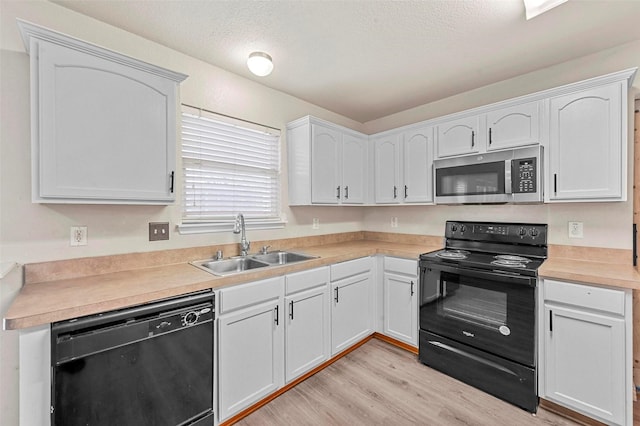 kitchen featuring sink, white cabinetry, black appliances, a textured ceiling, and light wood-type flooring