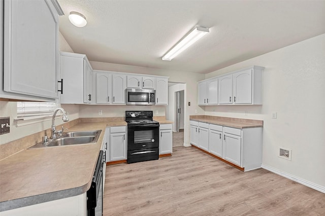 kitchen featuring dishwasher, white cabinetry, sink, and black / electric stove