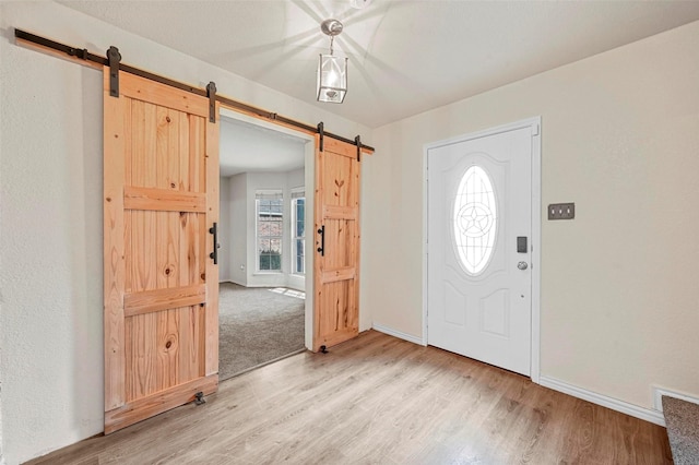 foyer entrance with a barn door and light hardwood / wood-style flooring