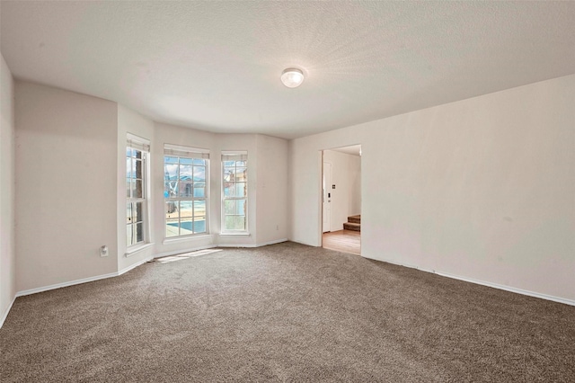 empty room with a textured ceiling and carpet flooring