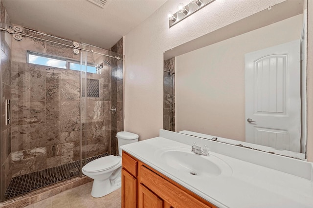 bathroom with a shower with door, vanity, tile patterned flooring, and toilet