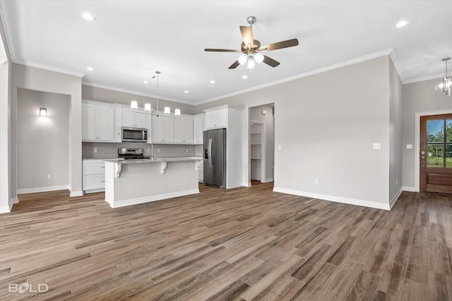 kitchen with hanging light fixtures, a breakfast bar area, white cabinets, and appliances with stainless steel finishes