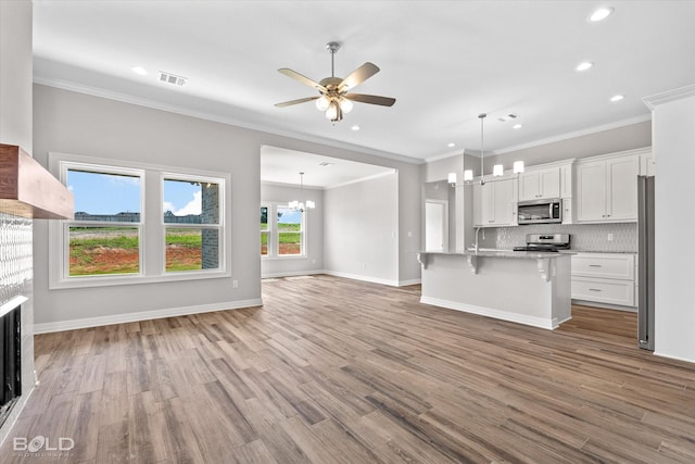 kitchen with stainless steel appliances, a kitchen bar, a kitchen island with sink, and white cabinets