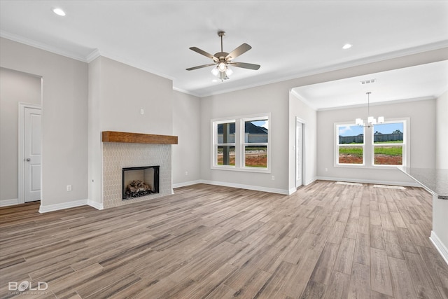 unfurnished living room with crown molding, ceiling fan with notable chandelier, and light hardwood / wood-style floors