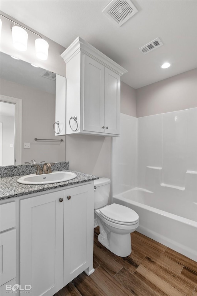 full bathroom with washtub / shower combination, wood-type flooring, toilet, and vanity