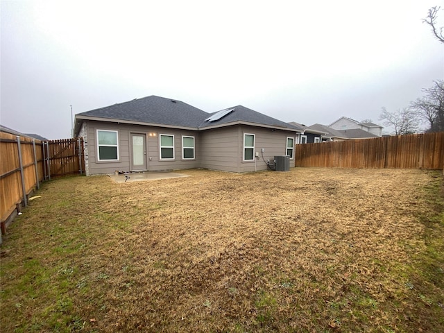 rear view of property with a patio area, central AC unit, and a lawn