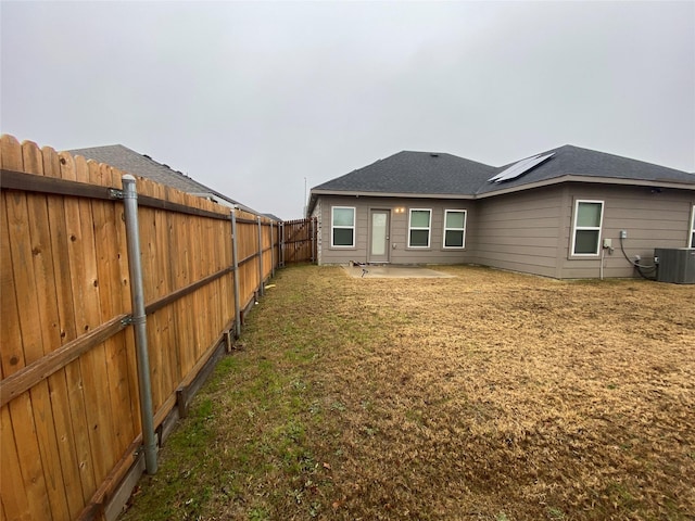 rear view of house with solar panels, a patio area, cooling unit, and a lawn