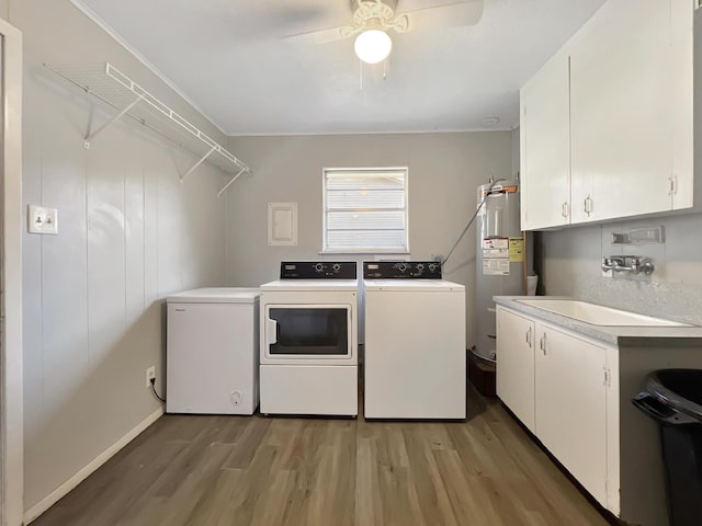 laundry area featuring sink, washer and clothes dryer, hardwood / wood-style floors, cabinets, and electric water heater