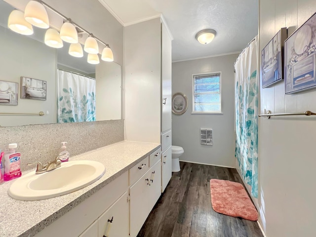 bathroom with crown molding, vanity, heating unit, wood-type flooring, and toilet