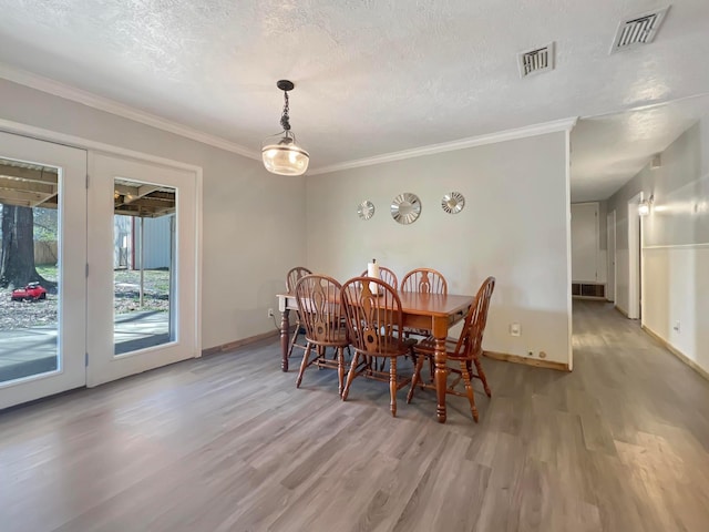 dining room featuring hardwood / wood-style floors, crown molding, and a textured ceiling