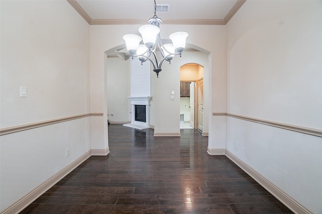 unfurnished dining area with crown molding, dark wood-type flooring, an inviting chandelier, and a fireplace