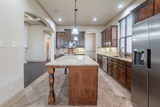 kitchen featuring sink, decorative light fixtures, a center island, stainless steel appliances, and decorative backsplash