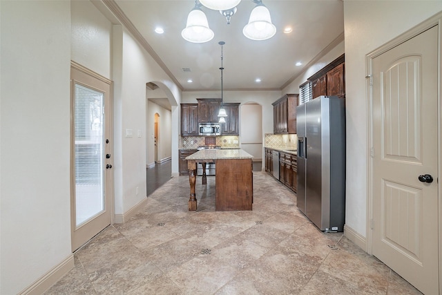 kitchen with appliances with stainless steel finishes, decorative light fixtures, a center island, and a kitchen breakfast bar