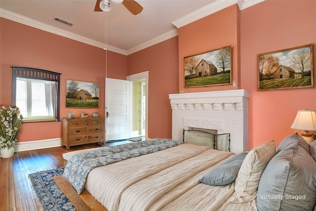 bedroom with dark hardwood / wood-style flooring, a brick fireplace, crown molding, and ceiling fan