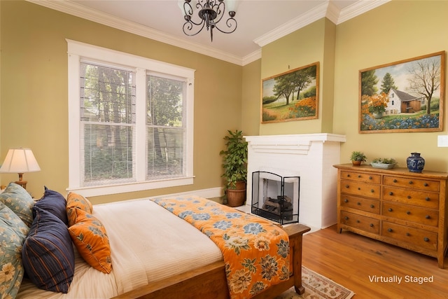 bedroom featuring an inviting chandelier, a brick fireplace, ornamental molding, and light hardwood / wood-style floors