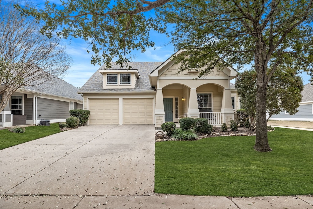 view of front of home with a garage, covered porch, and a front lawn