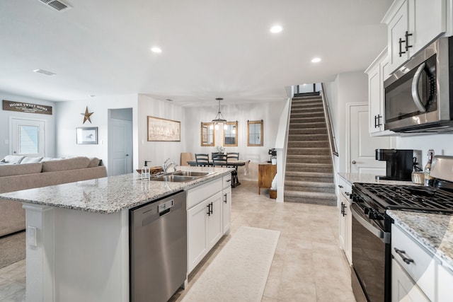 kitchen with stainless steel appliances, an island with sink, sink, and white cabinetry